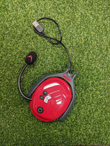 Das Protos BT COM in rot auf grünem Rasen mit Ladekabel